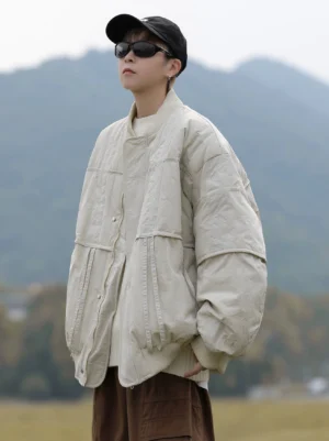 Three-quarter view of an oversized beige off-white bomber jacket with hidden snap placket, relaxed fit, textured padding, and casual Korean streetwear styling