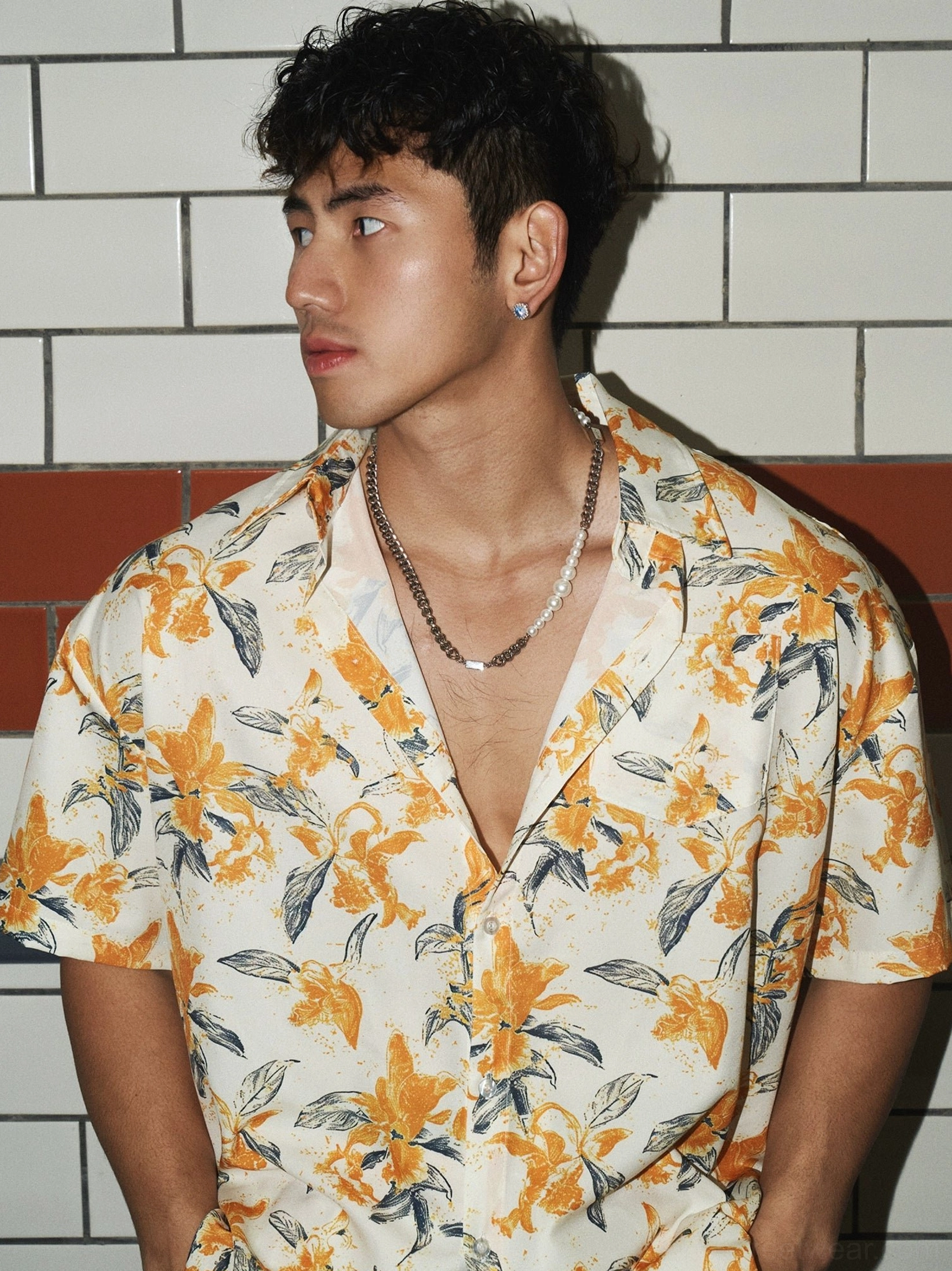 Close-up side view of an oversized orange and cream tropical floral camp shirt with short sleeves, notch collar, and grey leaf print