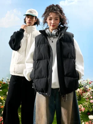 Unisex oversized quilted puffer vest with high stand collar shown in black and white streetwear colorways outdoors
