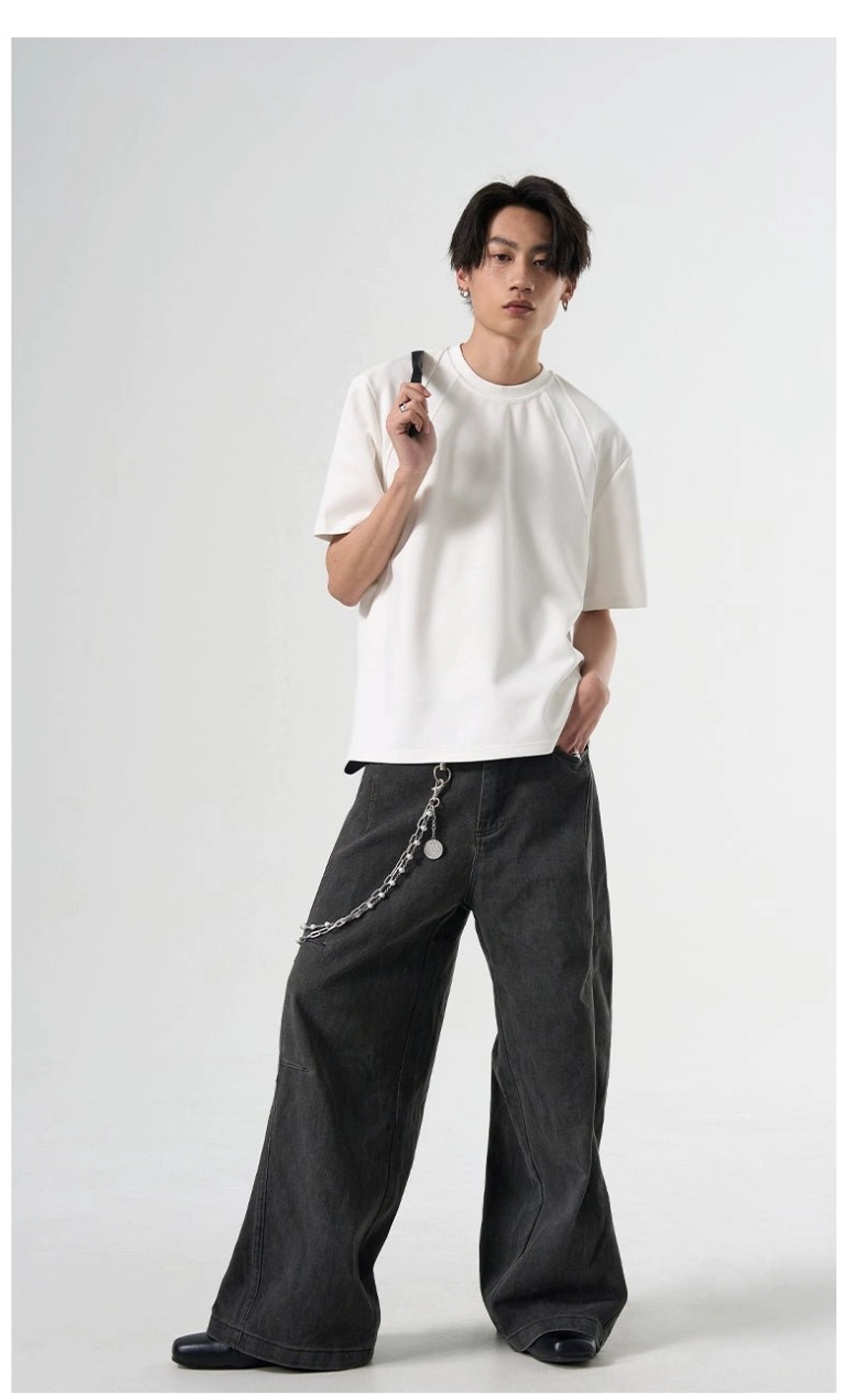 White relaxed raglan sleeve T-shirt shown in a full-body outfit with dark gray wide-leg pants and chain decoration