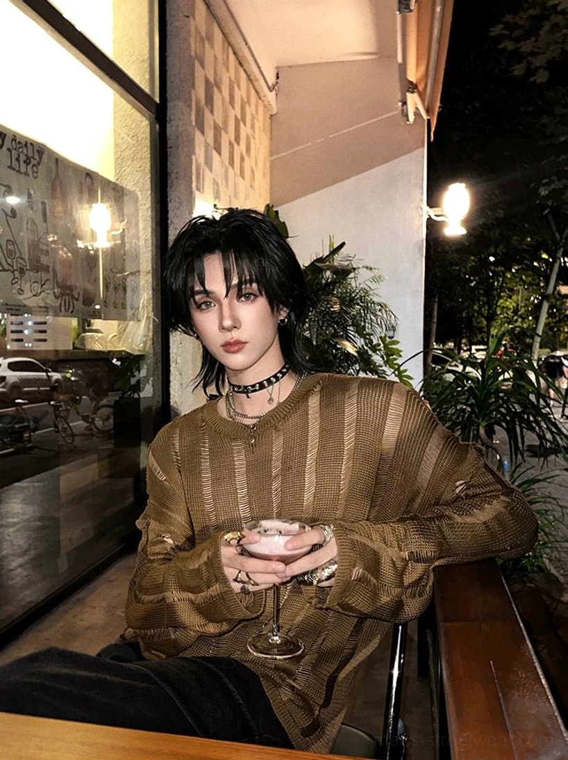 Side view of a relaxed oversized sheer distressed knit sweater showing the crew neck dropped shoulders and loose sleeves beside a cafe window