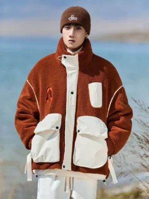 Male model wearing an oversized sherpa expedition jacket with a high stand collar and large utility pockets in an outdoor lakeside setting
