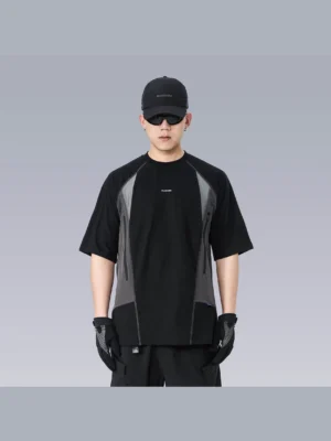 Front view of an oversized black and grey techwear panel T-shirt with relaxed fit, short sleeves, small chest graphic, black cargo pants, cap, and gloves