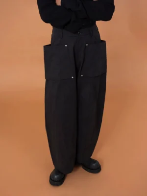 Black oversized utility cargo pod pants with exaggerated balloon legs, oversized front patch pockets, metal snap details, and wide-leg Korean streetwear styling