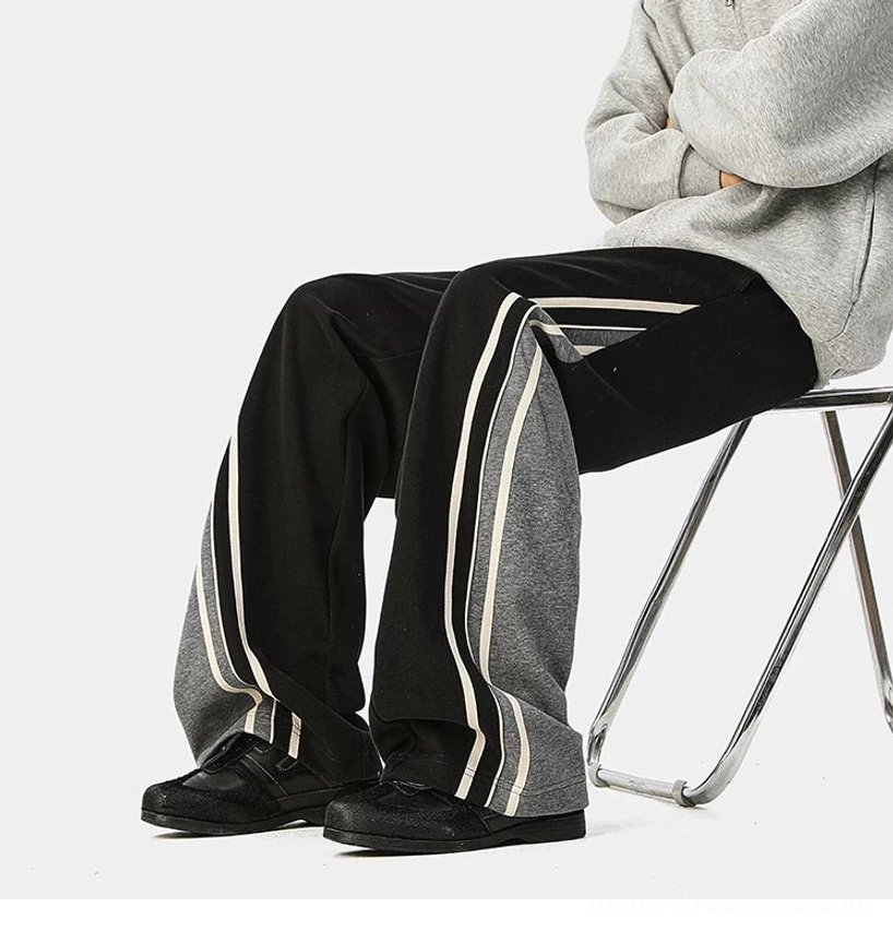Oversized varsity track pants with wide legs, adjustable waist, and graphic side stripe detailing for urban outfits
