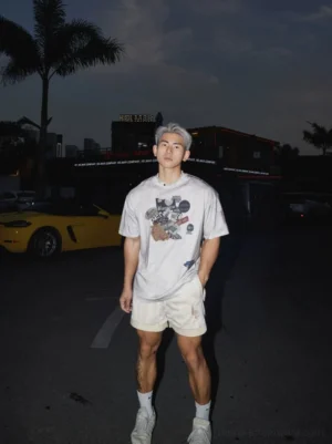 Front view of oversized vintage badge graphic T-shirt styled with beige shorts and white sneakers for a relaxed Korean streetwear outfit