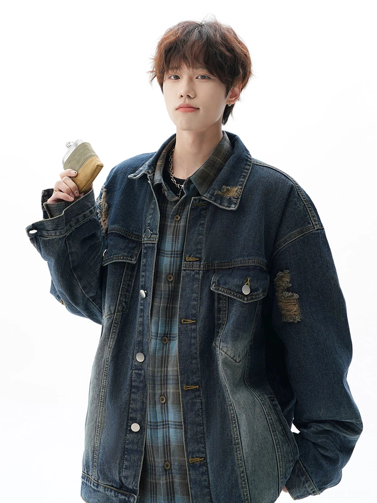 Blue oversized vintage distressed denim jacket with faded wash, sleeve patches, chest pockets, and layered plaid shirt streetwear styling