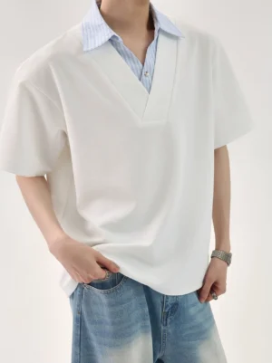 Front close-up of an oversized white faux layered streetwear T-shirt with blue striped shirt collar and V-neck placket styled with faded blue jeans