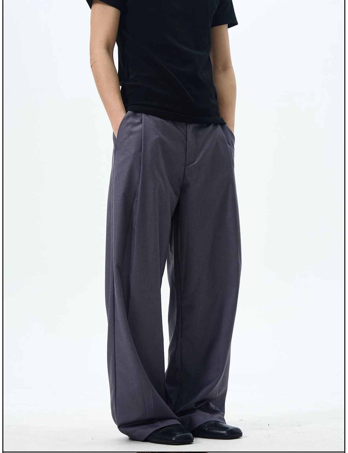 Side detail view showing the oversized wide leg shape and pleated construction of slate grey dress pants