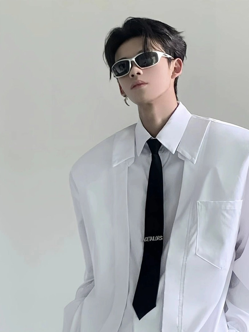 Close-up of white oversized wide-shoulder dress shirt showing broad collar cotton blend fabric chest pocket and black necktie styling