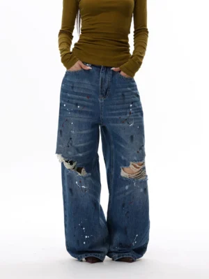 Front view of blue paint splatter distressed ultra wide leg denim jeans with faded wash and shredded knee holes