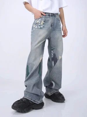 Side front view of high waist light blue distressed wide leg jeans featuring faded denim, paint marks, and ripped details