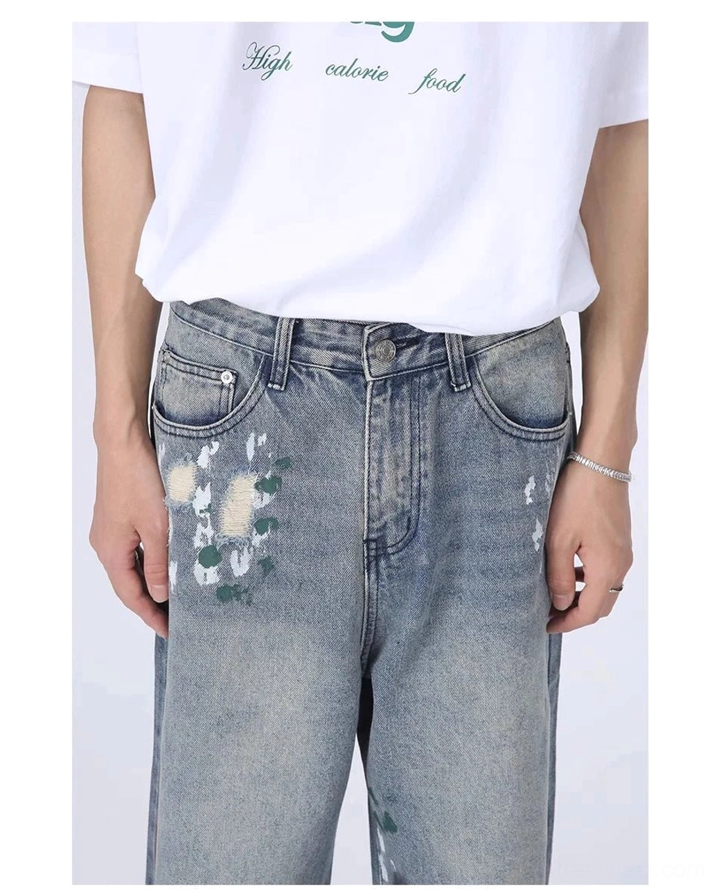 Close-up of button fly waistband, belt loops, front pockets, faded wash, and paint splatter details on wide leg denim jeans