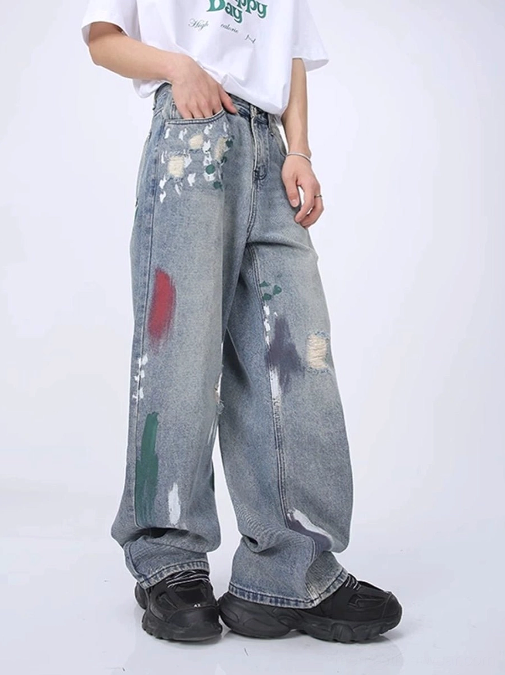 Front three-quarter view of light blue paint splatter distressed wide leg streetwear jeans with frayed rips and faded vintage wash