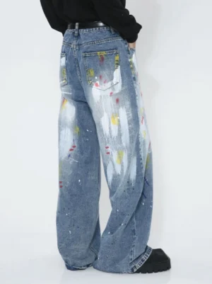 Rear view of faded blue paint splatter wide-leg jeans showing back pockets, stitching, and artistic denim details
