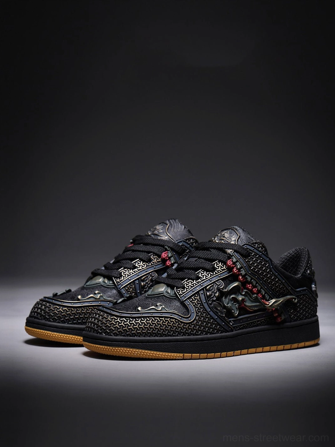 Pair of black dragon embroidered low-top sneakers displaying bronze hardware, red bead accents, and layered side panels