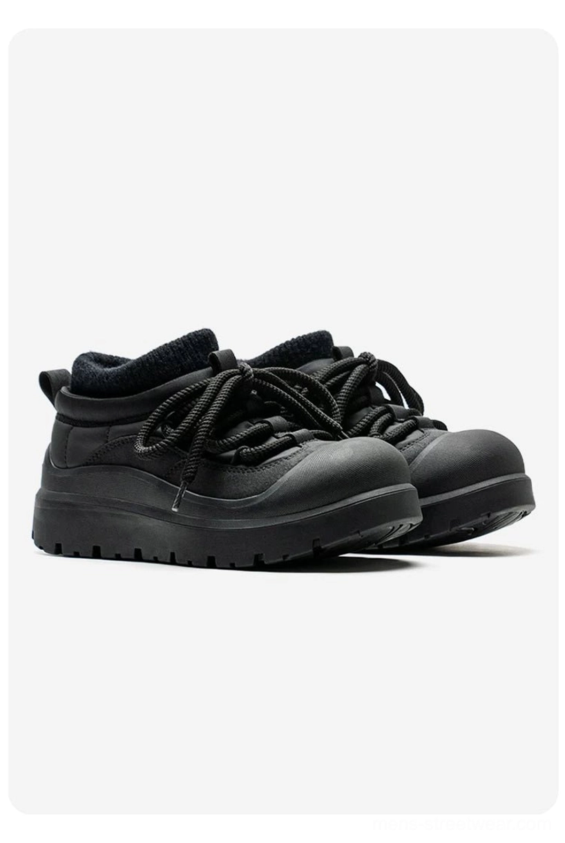 Pair of black fleece-lined platform sneakers shown from a front three-quarter view with ribbed collar and chunky raised rubber sole