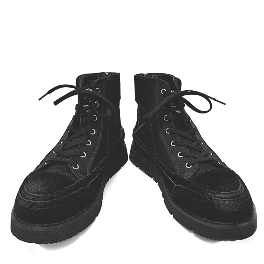 Pair of black high-top casual work boots displayed on white fabric with mixed suede and canvas upper and full lace system
