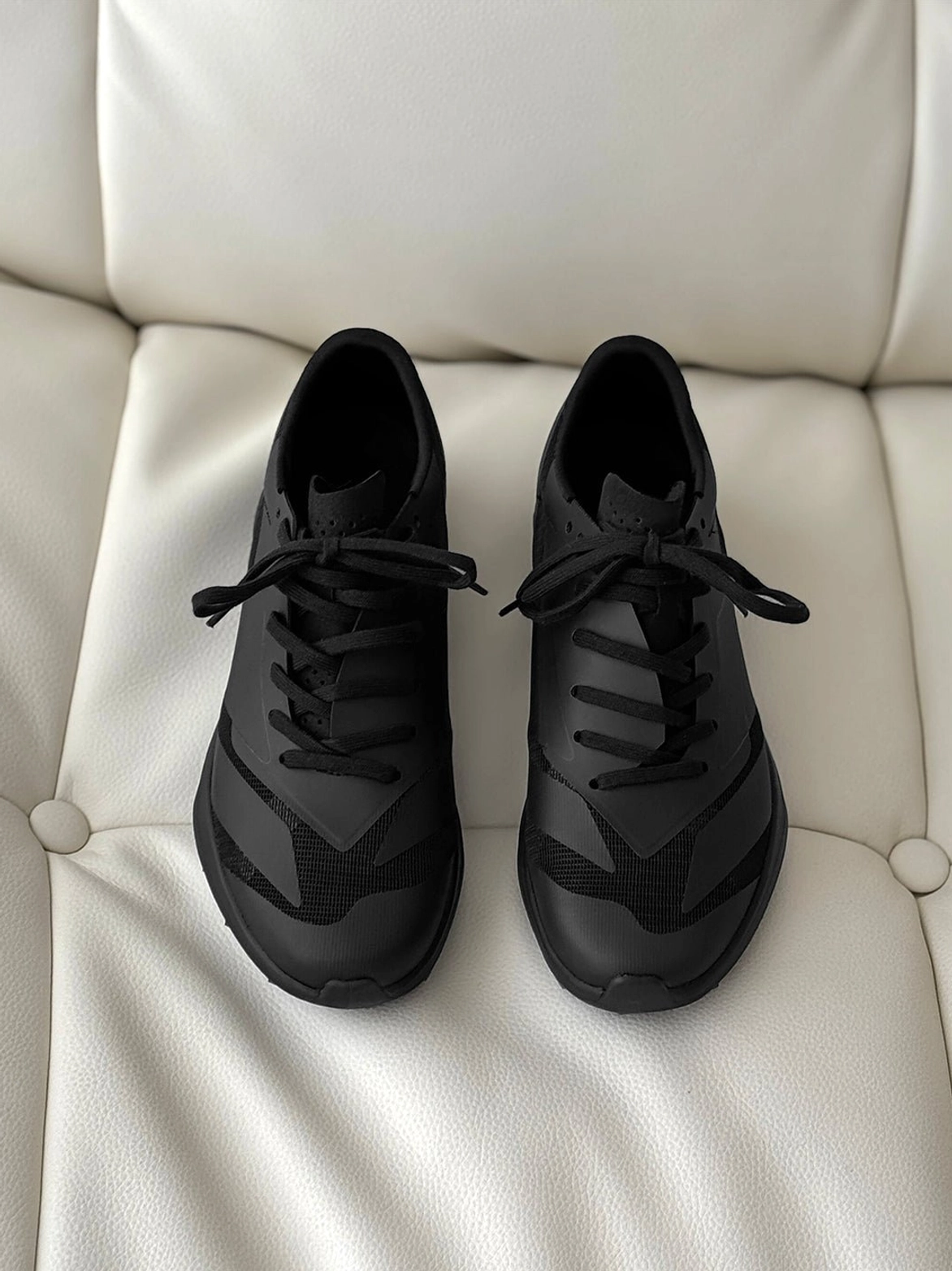 Top-down product view of a pair of black Korean streetwear sneakers with neatly tied laces and coordinated geometric upper paneling