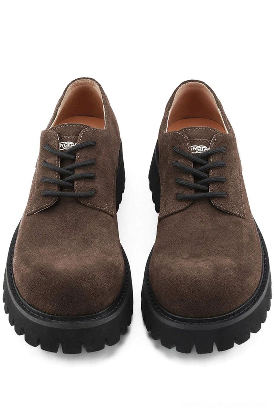 Pair of brown suede lug-sole derby shoes shown from the front with rounded toes, black laces, and chunky treaded soles