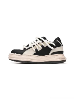 Two-tone paneled wavy platform sneakers in black and beige shown from the side with chunky round laces and a distressed thick outsole