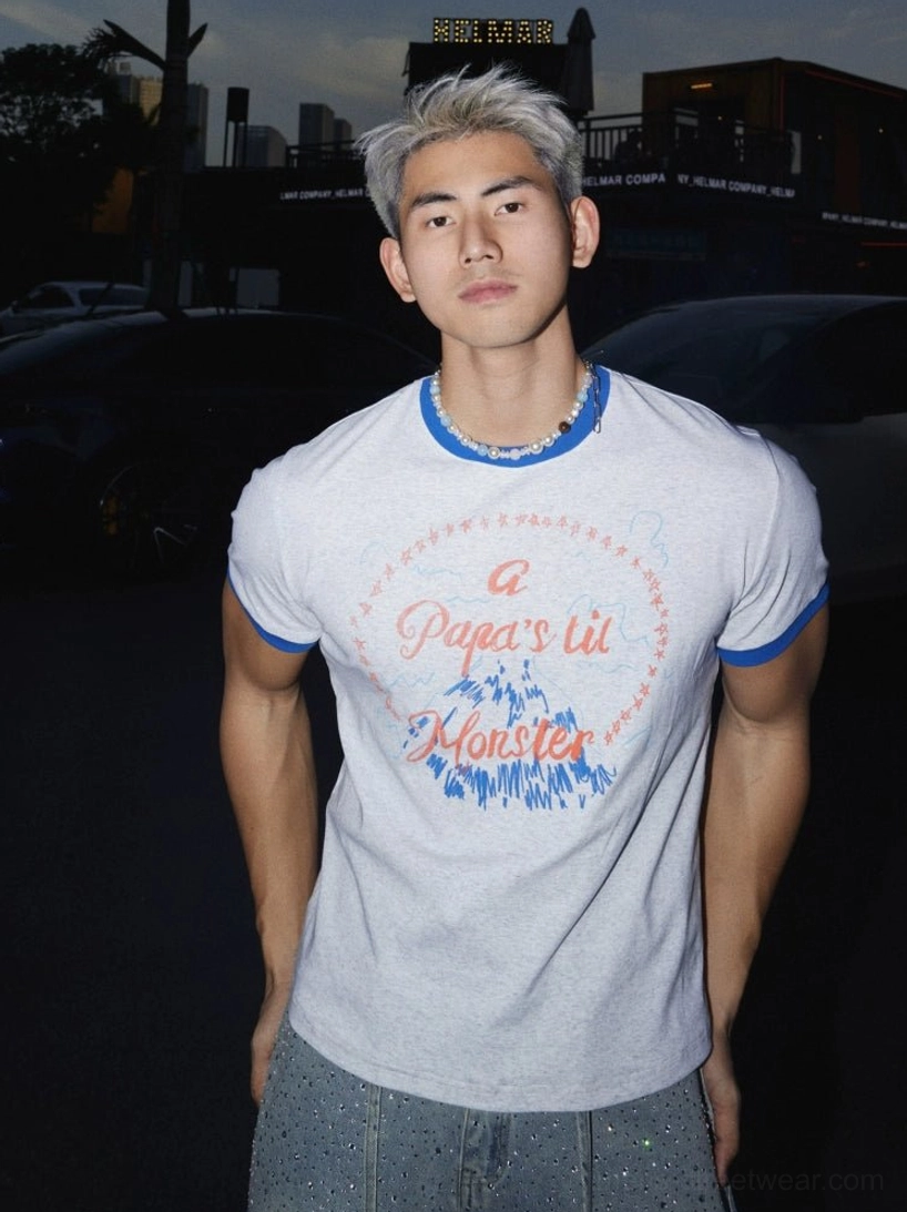 Front close-up of light grey Papa's Lil Monster graphic ringer tee with blue contrast collar and sleeve cuffs styled with a pearl beaded necklace