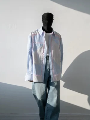 Pastel geometric patchwork pinstripe oversized shirt front view styled with wide-leg jeans in a sunlit studio