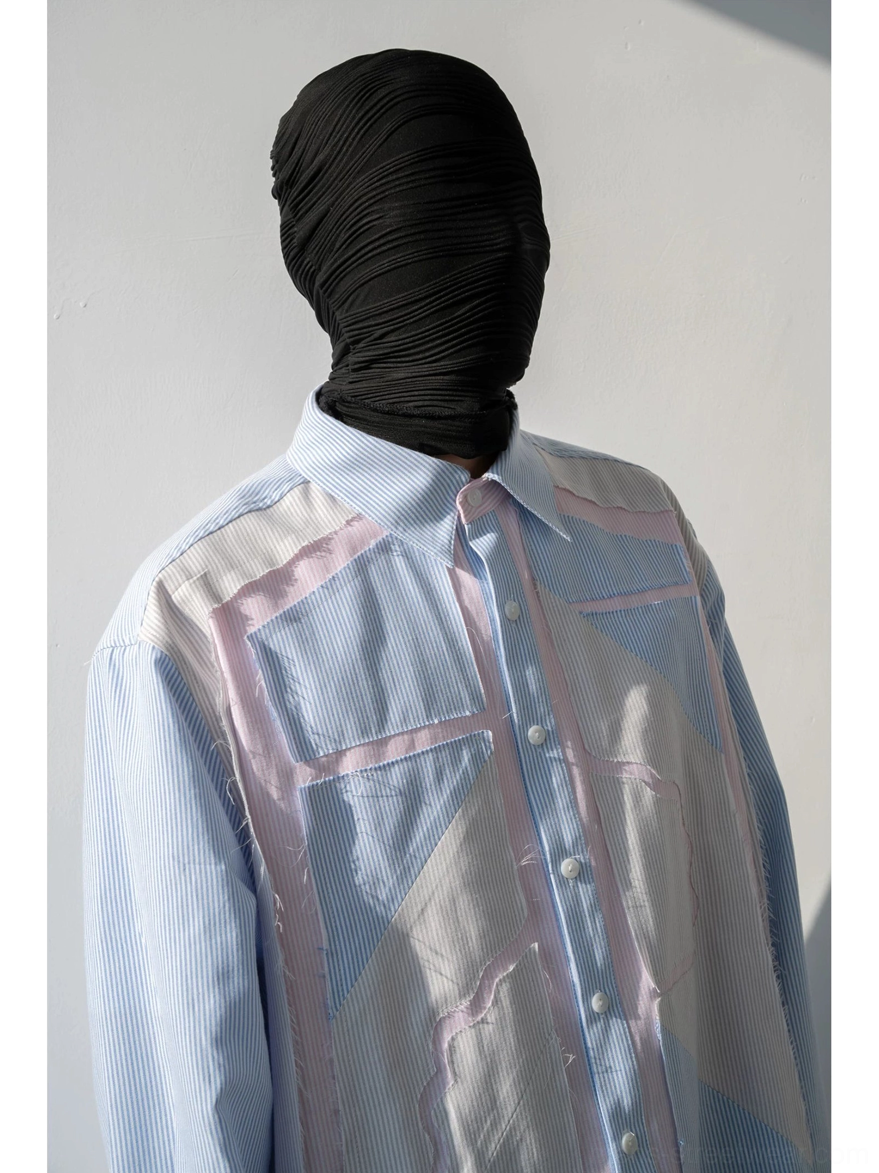 Close-up of pastel geometric patchwork pinstripe shirt showing clear buttons pink trim and striped fabric