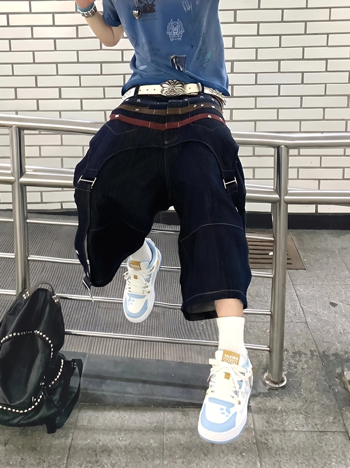 Paw print low-top court sneakers worn with cropped workwear trousers on outdoor stairs in a casual streetwear outfit