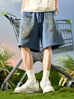 Peacock Blue graffiti print drawstring sweat shorts styled with cream T-shirt and white skate sneakers outdoors