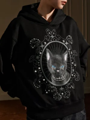 Close-up of pearl embellished mystic cat graphic and gem-style cat eyes on black oversized hoodie