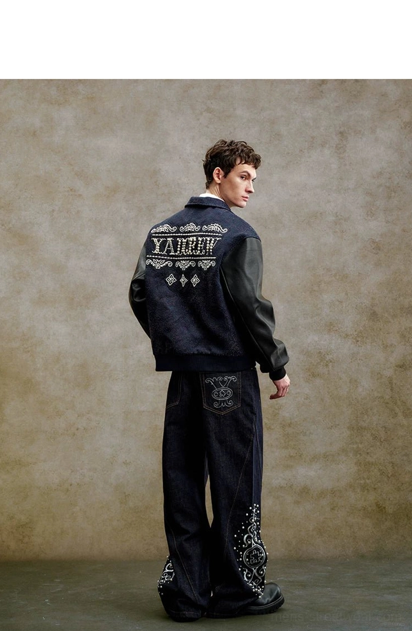 Back side view of a relaxed pearl embellished navy varsity jacket styled with embroidered dark denim, ribbed hem, and ribbed cuffs