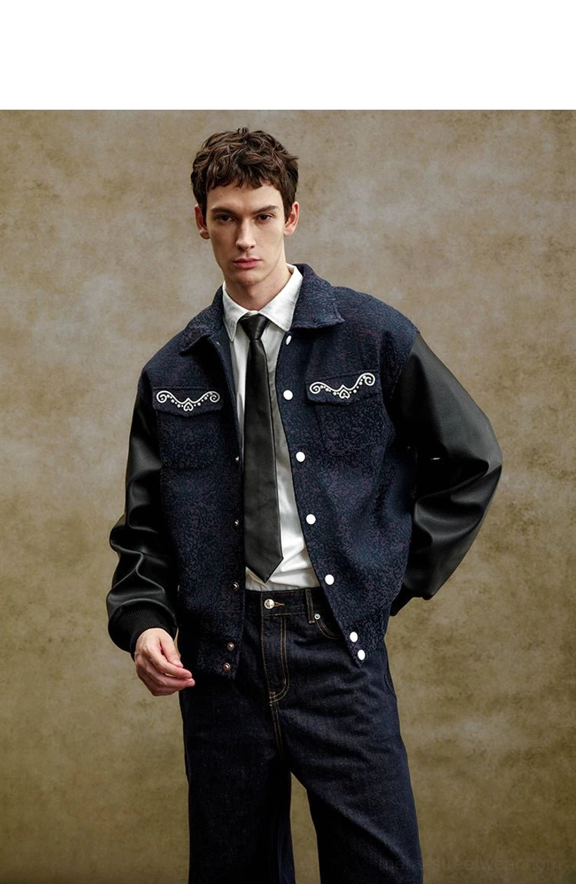 Open front view of a pearl embellished navy varsity jacket layered over a shirt and tie, showing chest embellishment and black faux leather sleeves