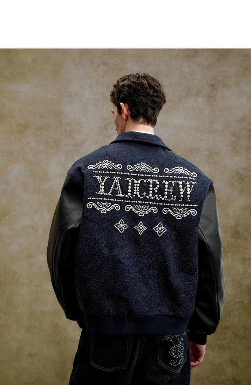 Close-up back detail of a pearl embellished varsity jacket with neatly arranged ornate scroll embroidery, oversized lettering, and diamond motifs
