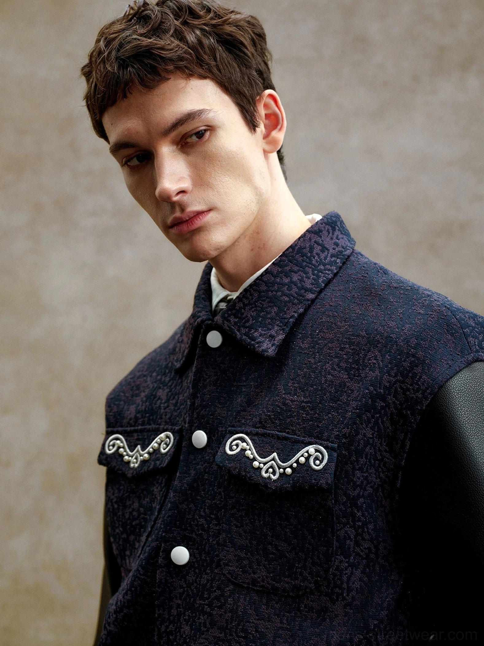 Close-up front view of navy pearl embellished varsity jacket showing shirt collar, snap-button placket, chest pockets, and detailed pearl embroidery