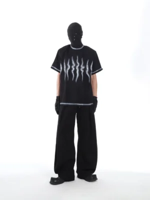 Black Phantom Pulse oversized airbrush graphic tee shown from the front with white spray-style scratch print, contrast trim, masked model, and wide-leg streetwear styling