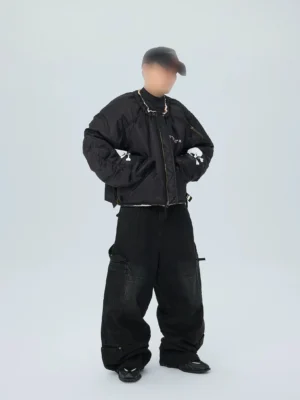 Three-quarter front view of black oversized skull puffer bomber jacket styled with black cargo pants and baseball cap