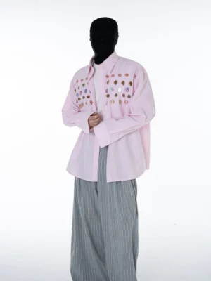 Pink gem embellished pinstripe oversized streetwear shirt worn with grey wide-leg trousers in front three-quarter studio view