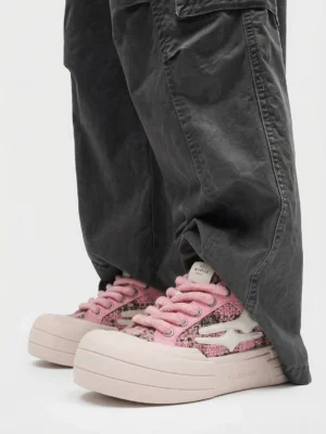 Pink glitter platform sneakers worn with dark gray cargo pants showing rounded toe and elevated pink sole