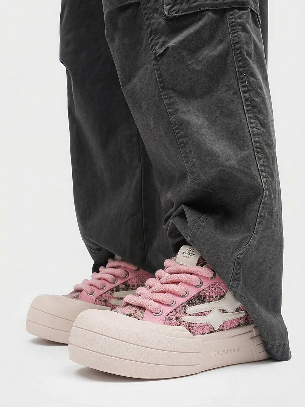 Pink glitter platform sneakers worn with dark gray cargo pants showing rounded toe and elevated pink sole