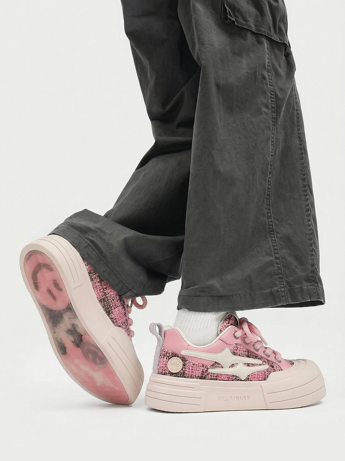 Rear side view of pink tweed platform sneakers worn with gray cargo pants showing heel and patterned outsole