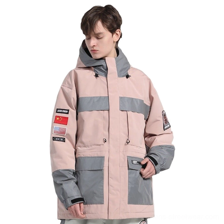 Pink unisex reflective color block ski jacket worn in a front three-quarter view with gray hood accents and utility cargo pockets