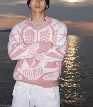 Front view of relaxed fit pink and white geometric star knit sweater styled with a black beanie and white drawstring shorts for Korean streetwear