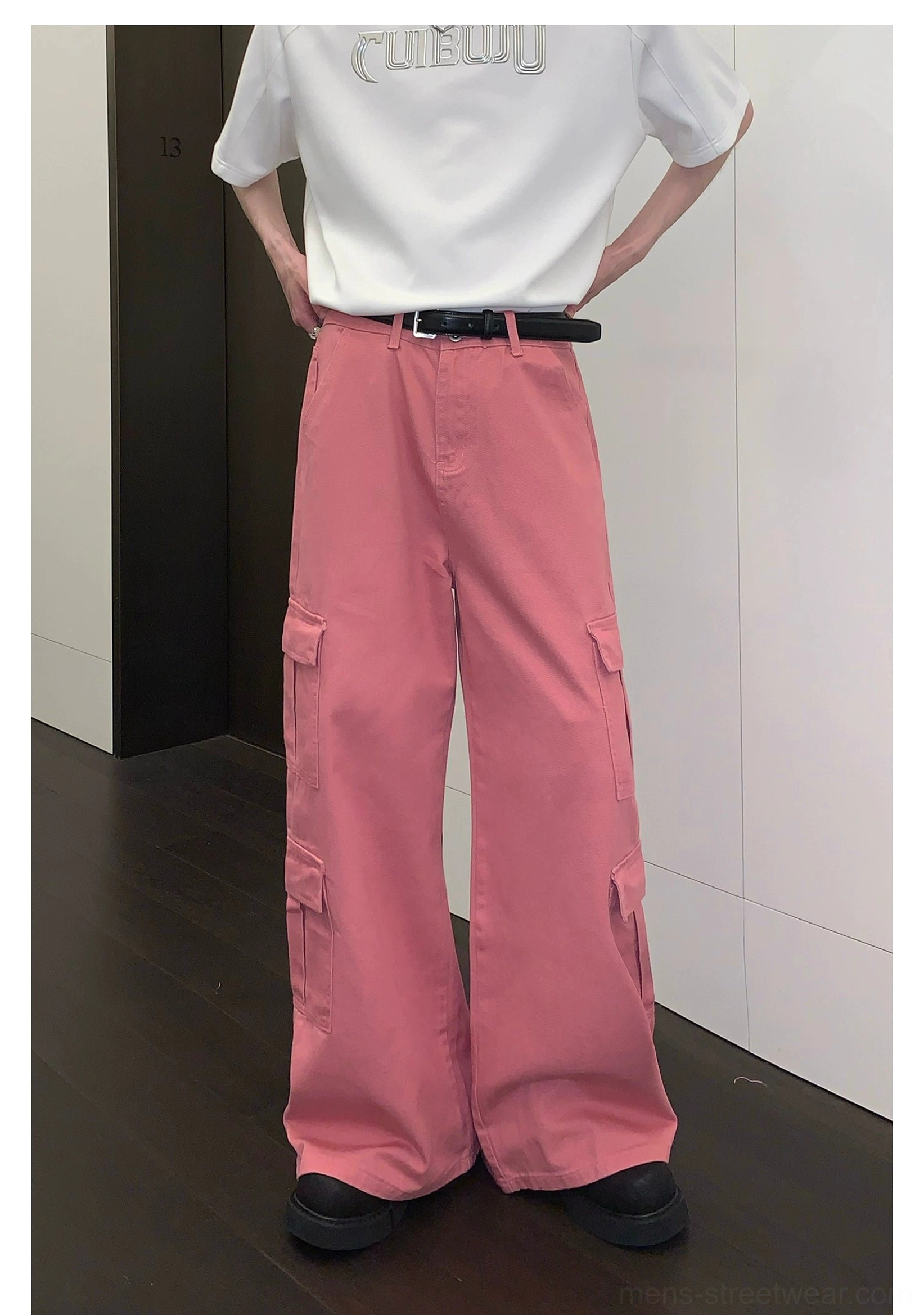 Front view of pink wide-leg cargo trousers with hands placed in the back pockets and relaxed flowing legs