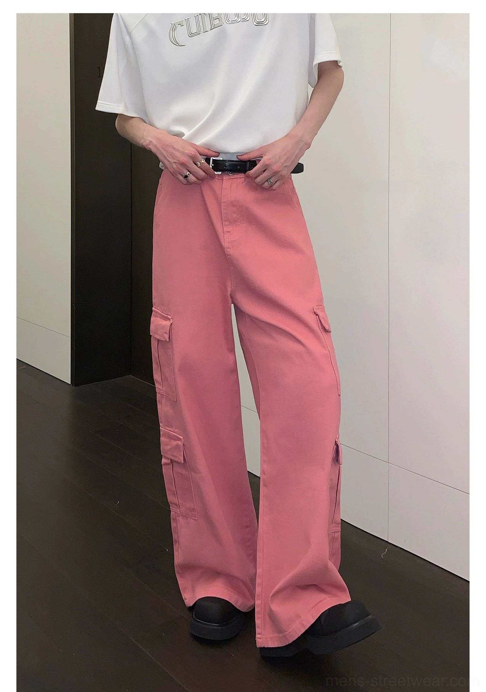 Front right three-quarter view of pink utility cargo pants featuring oversized side pockets and loose wide-leg styling