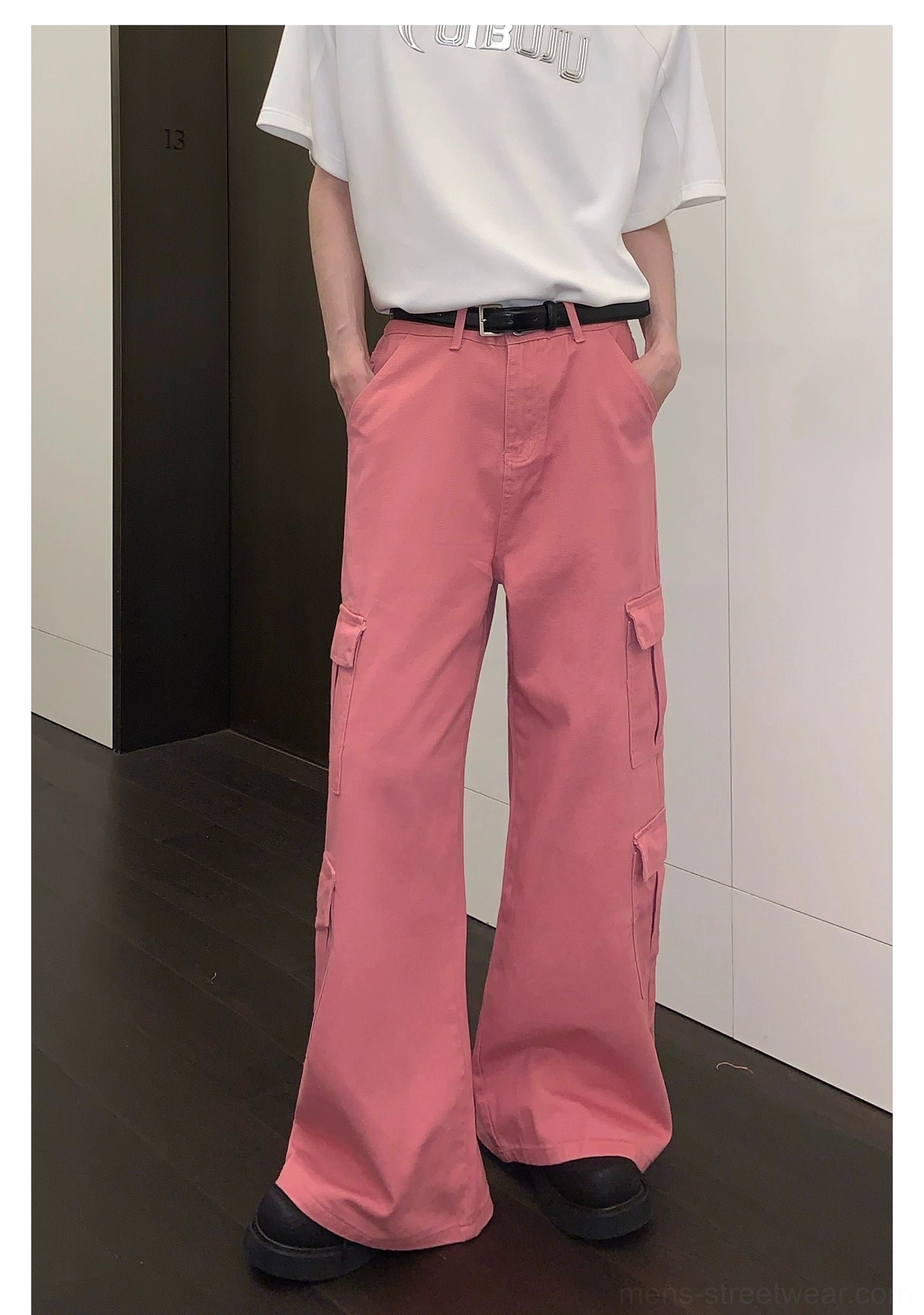 Front view of solid pink cargo pants with structured flap pockets, full-length legs, white T-shirt, and black loafers