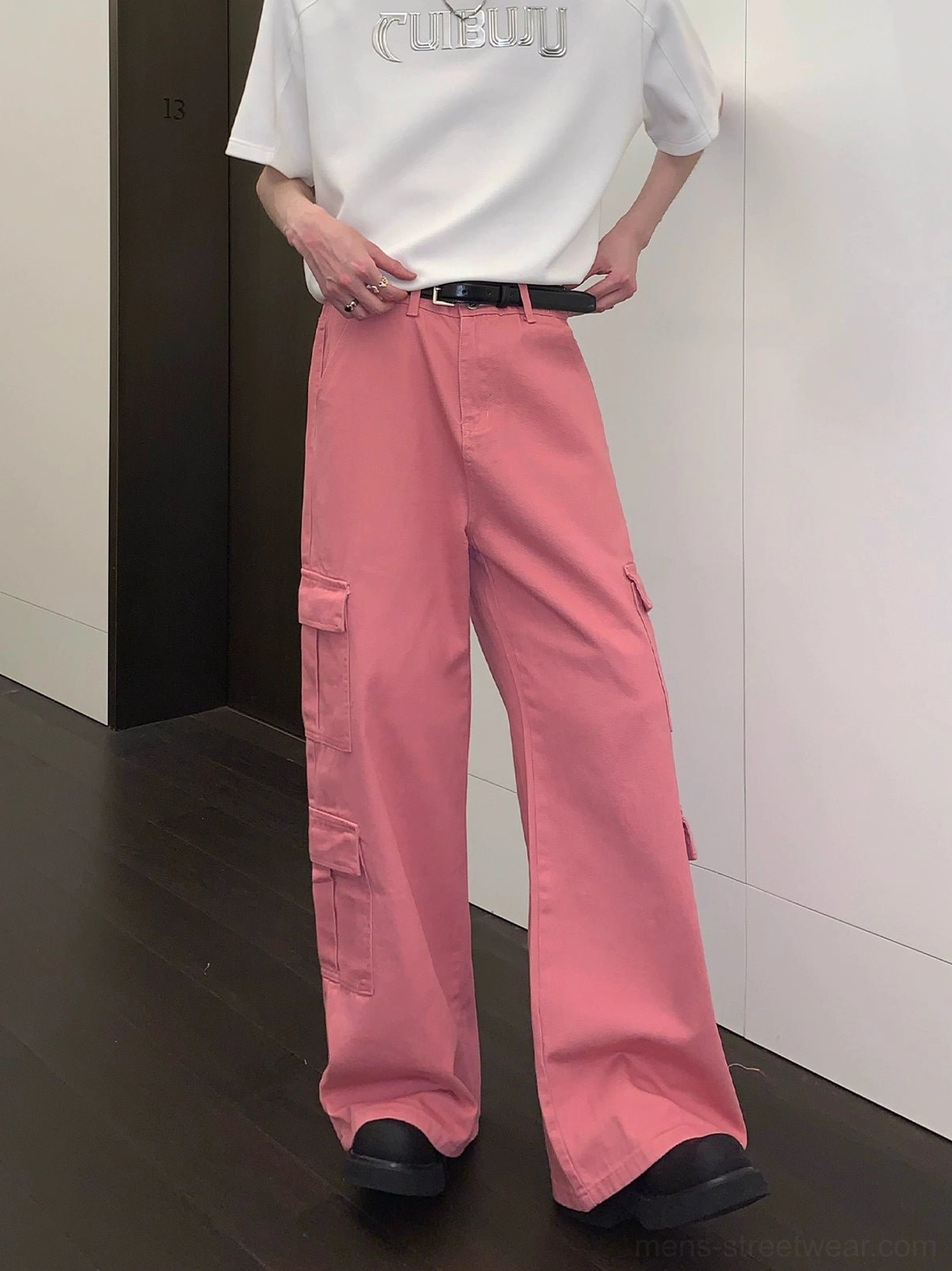 Front view of pink wide-leg cargo pants with relaxed streetwear fit, multiple flap pockets, white graphic T-shirt, black belt, and loafers
