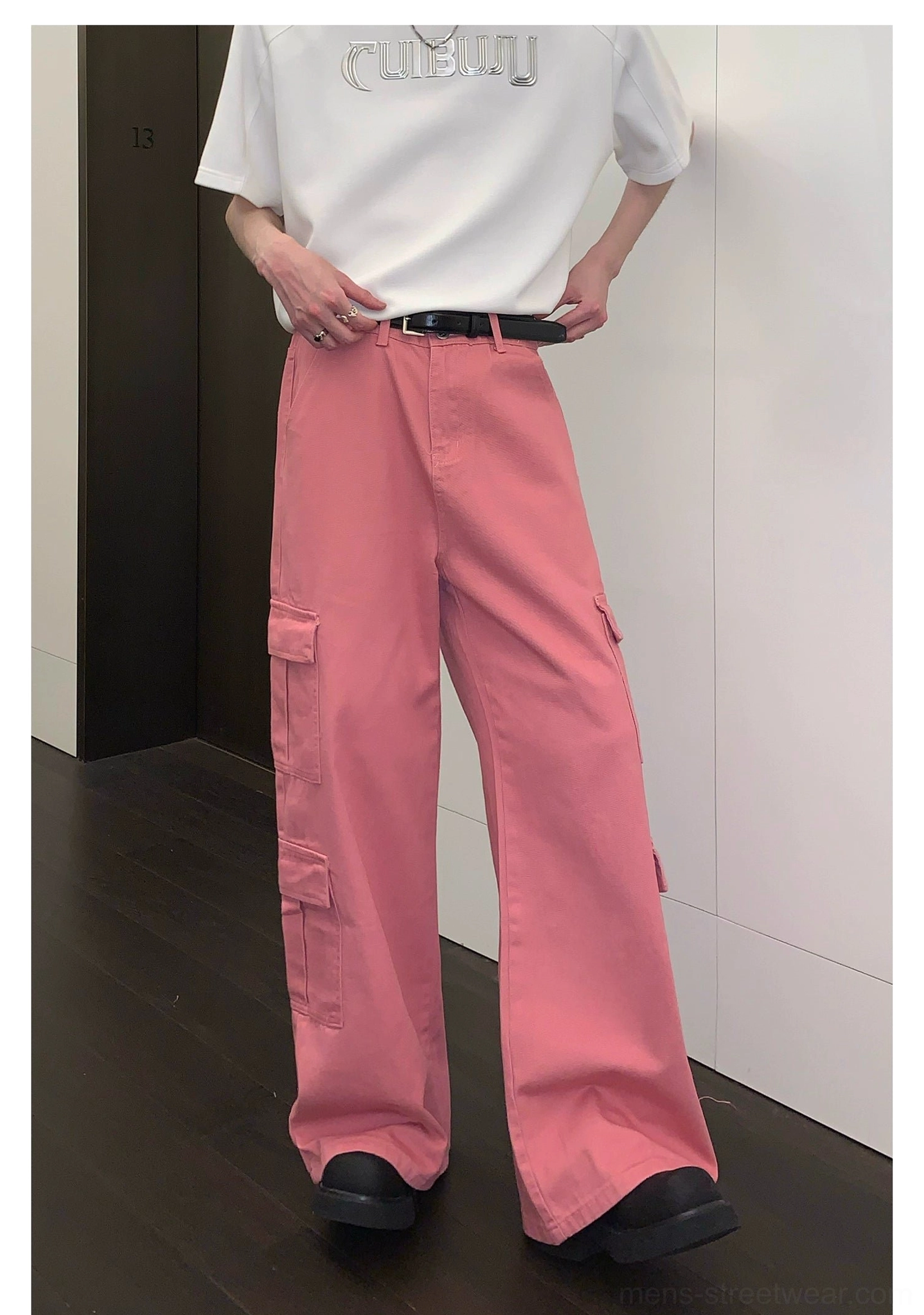 Front left three-quarter view of pink cargo pants with visible zip fly, belt loops, and structured side cargo pockets