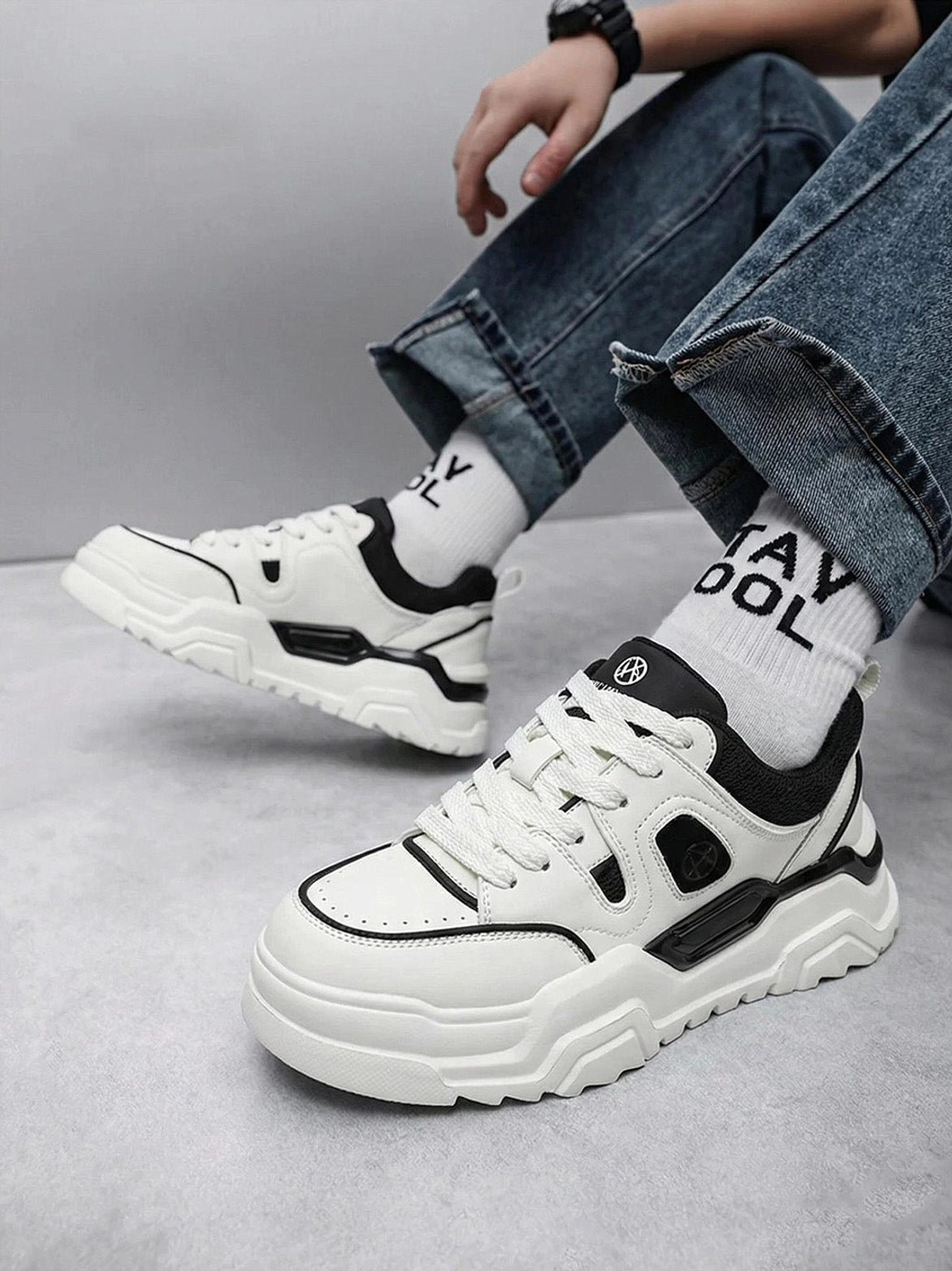 Overhead front view of person wearing black and white geometric cutout platform sneakers with blue jeans and crew socks street style