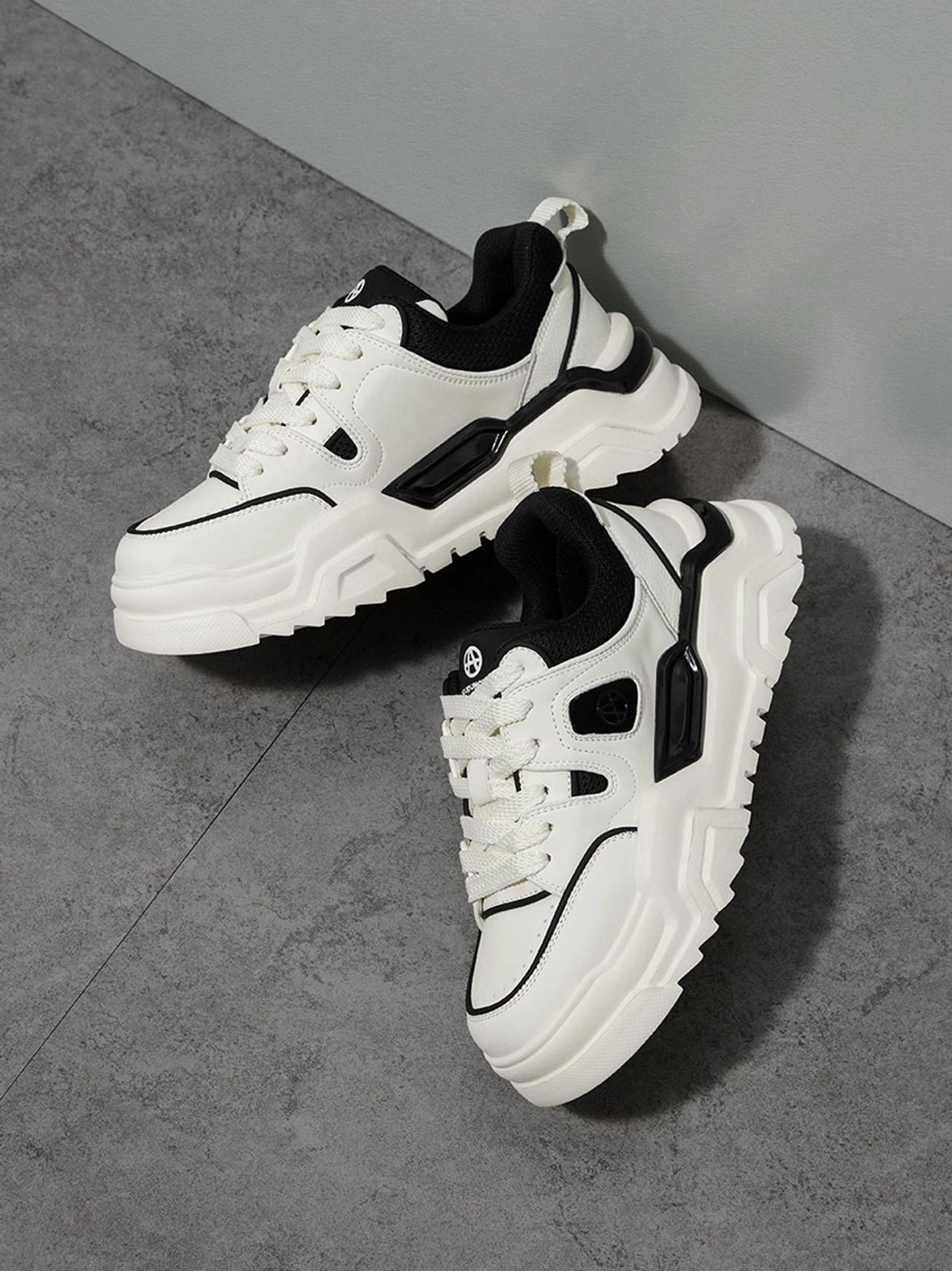 Paired white and black platform sneakers side oblique overhead showing complete lug sole profile and exposed inner lining architecture